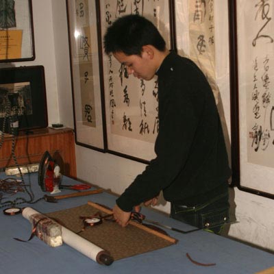 Preparing to add the ribbon to a wall scroll
